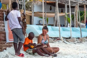 Tourist learning local customs from a boy while sitting on the beach