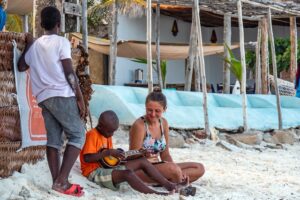 Tourist learning local customs from a boy while sitting on the beach