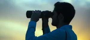 A person looking into the distance through binoculars