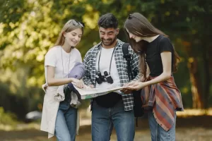 Three happy people examining a map together in a sunlit forest