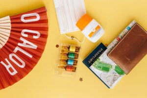 Map and a passport in a leather wallet next to sun cream and a mask